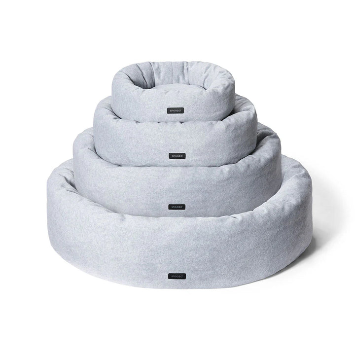 Various sizes of the Snooza Self-Warming Polar Fleece Cuddler beds stacked together on a white background.