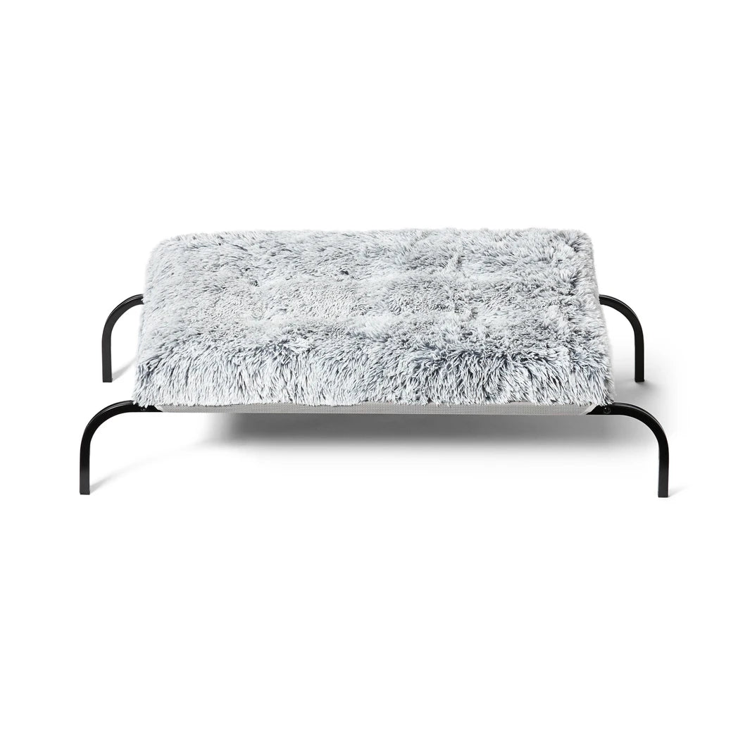 Snooza Calming Multimat - Silver Fox with Raised Bed: A dog resting on a secure mat attached to a Snooza Raised Bed using velcro tabs.